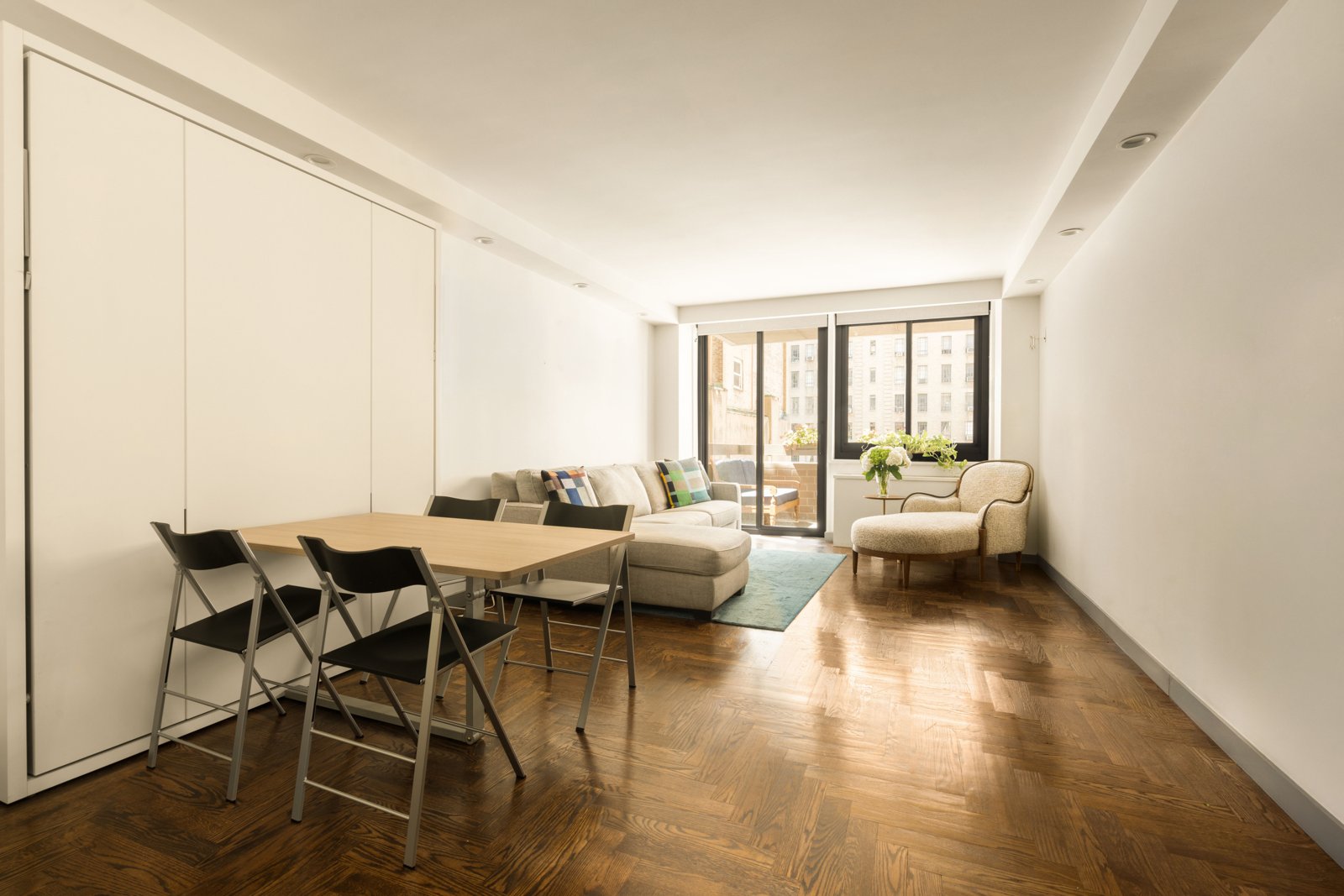 The fold-down dining table with four chairs, set before the south window
